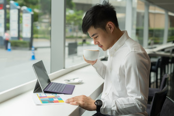 Handsome Asia businessman using laptop and analysis graph visualization at coffee shop