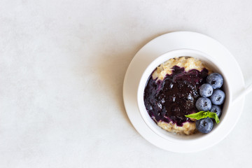 Porridge with blueberry sauce decorated fresh blueberries and mint. 