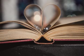 Wedding rings in book with heart shaped pages