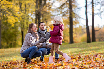family, season and people concept - happy mother, father and little daughter with maple leaves at...