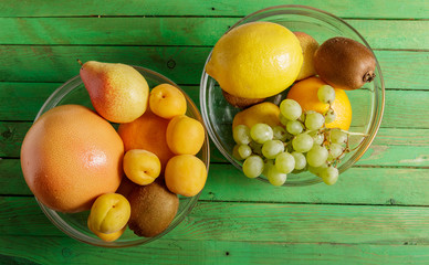 Fruit in a glass dish on a green wooden background.
