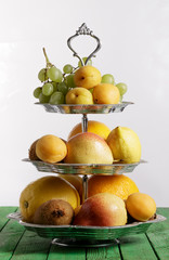 Fruit on stand on green wooden background.
