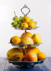 Fruit on stand on blue wooden background.