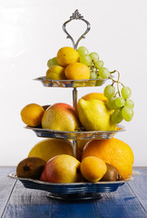 Fruit on stand on blue wooden background.