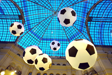 soccer balls hanging in the air in the room under a glass roof.