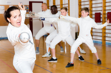 Young woman fencer practicing effective fencing techniques in training room