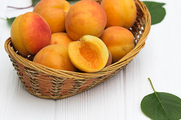 Ripe apricots in basket on white background