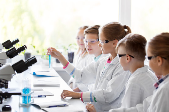 education, science and children concept - kids with test tubes studying chemistry at school laboratory