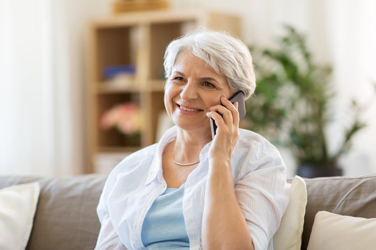 technology, communication and people concept - happy senior woman calling on smartphone at home
