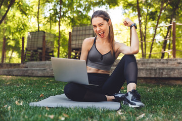 Portrait of a smiling young fitness girl using laptop