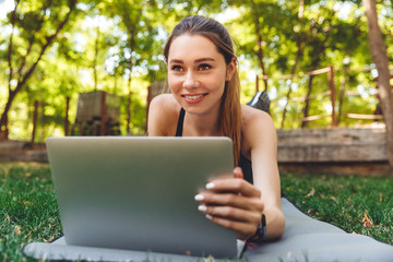 Portrait of a smiling young fitness girl using laptop