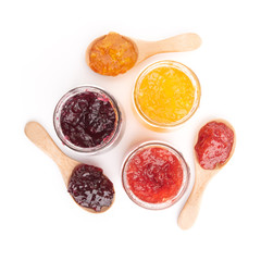 Open jar of strawberry, orange and blueberries  jam and a spoon, isolated on white, top view.