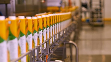 Plant juice. Juice packaging are moving on the conveyor belt - Powered by Adobe