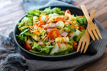 Salad with fusilli pasta accompanied tomatoes, mozzarella, smoked ham and italian cheese