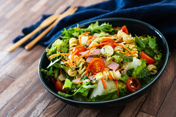 Salad with fusilli pasta accompanied tomatoes, mozzarella, smoked ham and italian cheese