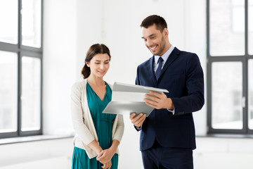 real estate business, sale and people concept - happy smiling realtor with folder showing documents to female customer at new office room