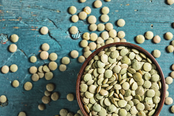 Green lentils with spoon on wooden background