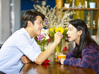 playful young asian couple in coffee shop