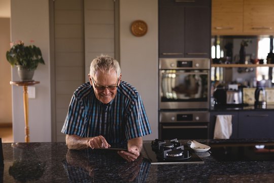 Senior man using digital tablet in kitchen