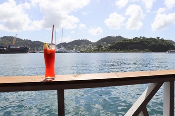 Ice cold drink on a rail with ocean and tropical island scenes in the background