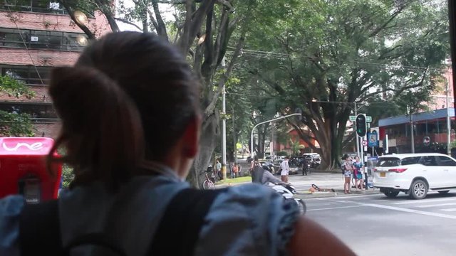 View from behind of a young woman looking out the window towards a busy street