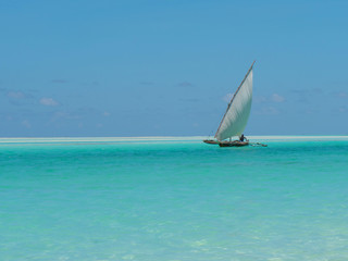 Fisherman fishing and sails on a wooden boat on clear blue water along a tropical exotic beach in Africa. Indian Ocean, Zanzibar