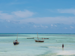 Fisherman fishing and sails on a wooden boat on clear blue water along a tropical exotic beach in Africa. Indian Ocean, Zanzibar