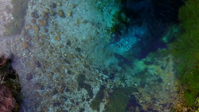 Aerial. The Blue Eye (Albanian: Syri i Kalter, is a water spring near Muzine in Vlore County, southern Albania. A popular tourist attraction. Mountains and river footage.