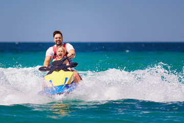 happy, excited family, father and son having fun on jet ski at summer vacation