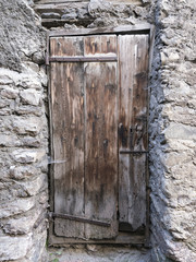 very old brown grungy door in ancient wall of medieval house in village of french provence