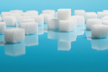 selective focus Group of Sugar cubes vary position on light blue background