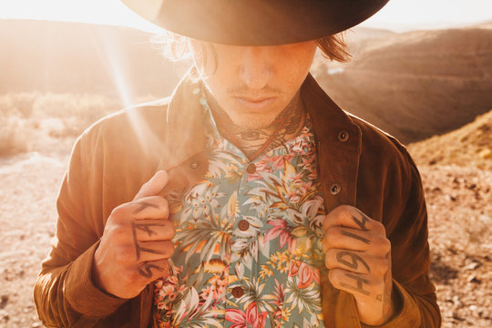 Stylish tattooed man in hat at summer