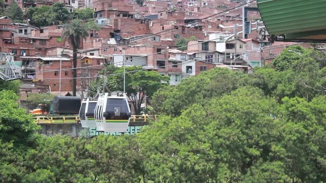 Metrocable cabins entering and leaving the station with favelas around