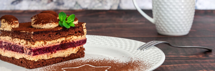 Panoramic view on piece of cake on a white plate with cocoa and fresh mint, a fork and a cup of tea