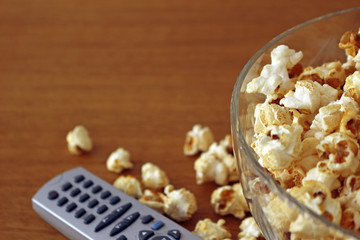 Popcorn in a bowl next to a tv remote controller