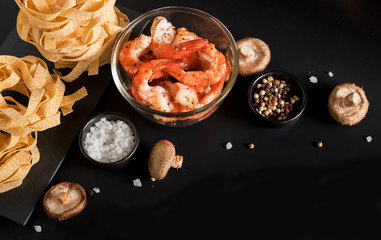 Fettuccine tagliatelle paste with prawns shrimps, herbs and spices on black