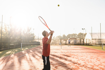Fototapeta na wymiar Young man is playing tennis on fresh sunny morning