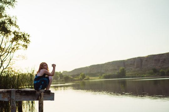 Sensual young woman sitting on pier