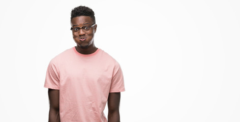 Young african american man wearing pink t-shirt puffing cheeks with funny face. Mouth inflated with...