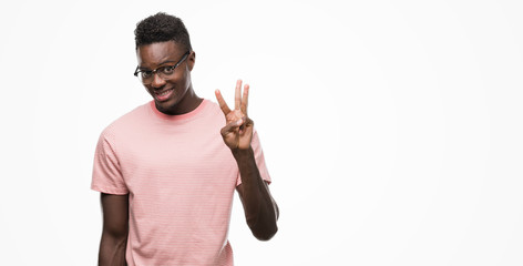 Young african american man wearing pink t-shirt showing and pointing up with fingers number three...