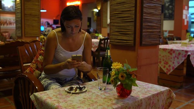 Thai food. A woman sitting in a restaurant takes pictures of fried insects on a plate.