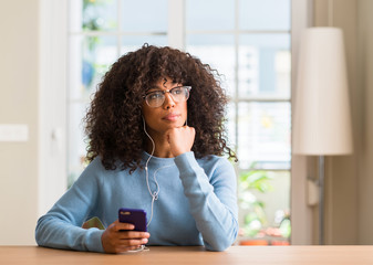 Beautiful african american woman using smartphone serious face thinking about question, very confused idea