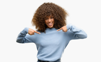 African american woman wearing a sweater looking confident with smile on face, pointing oneself...