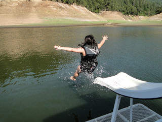 Young girl speeding down the slide of a houseboat in Shasta Lake