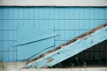 Blue wall of building with hatch and stairway close up. Steps against wall of blue tiles. Background with porch with copy space.
