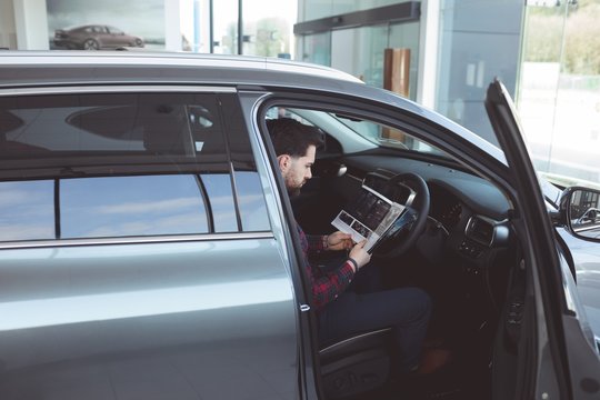 Salesman reading brochure inside the car