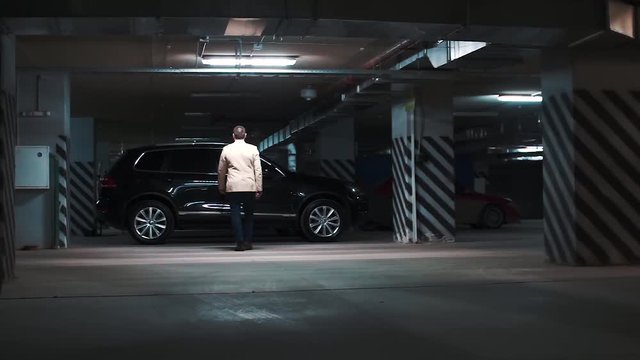 Mature Man In A Beige Jacket Takes The Car Off Guard In The Parking Lot