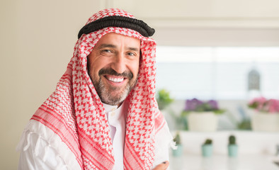 Middle age arabian man at home with a happy face standing and smiling with a confident smile...