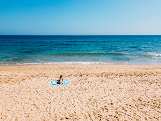 Fototapeta na wymiar Top Aerial Drone View Of Woman In Swimsuit Bikini Relaxing And Sunbathing On Round Turquoise Beach Towel Near The Ocean