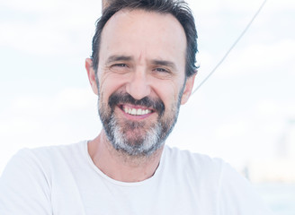 Fototapeta premium Handsome senior man traveling on sailboat and smiling happy and confident